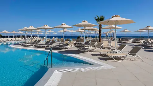 Poolområde med solstole og parasoller 
